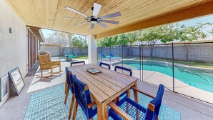 An outdoor patio with a wooden table and chairs, a ceiling fan, and a view of a swimming pool. - Modern home with open layout, private pool, & washer/dryer - dog friendly (Phoenix)