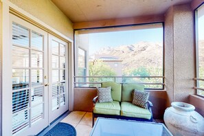 Ein Balkon mit einem grünen Sofa, einer großen Vase und Blick auf die Berge.
