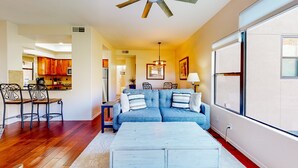 A living room with a sofa, coffee table, and dining area with chairs. - Beautiful condo with stunning views, pool, hot tub, balcony, W/D, AC (Tucson)