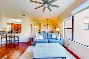 A living room with a sofa, coffee table, and dining area with chairs. - Beautiful condo with stunning views, pool, hot tub, balcony, W/D, AC (Tucson)