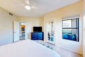 A bedroom with a bed, a dresser, a television, and a sliding glass door leading to an outdoor area. - Beautiful condo with stunning views, pool, hot tub, balcony, W/D, AC (Tucson)