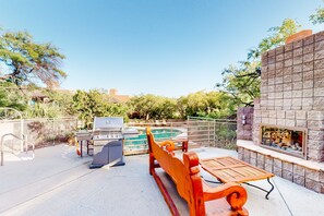 A patio area with a pool, a barbecue grill, a wooden bench, and a stone wall with a fireplace. - Beautiful condo with stunning views, pool, hot tub, balcony, W/D, AC (Tucson)