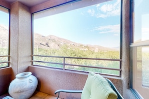 Ein Balkon mit Blick auf eine hügelige Landschaft, einem großen Blumentopf und einem grünen Kissen.
