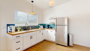 A modern kitchen with white cabinets, a stainless steel refrigerator, wooden countertops, and a window with blinds. - Inviting dog-friendly studio with full kitchen and central AC (Tucson)