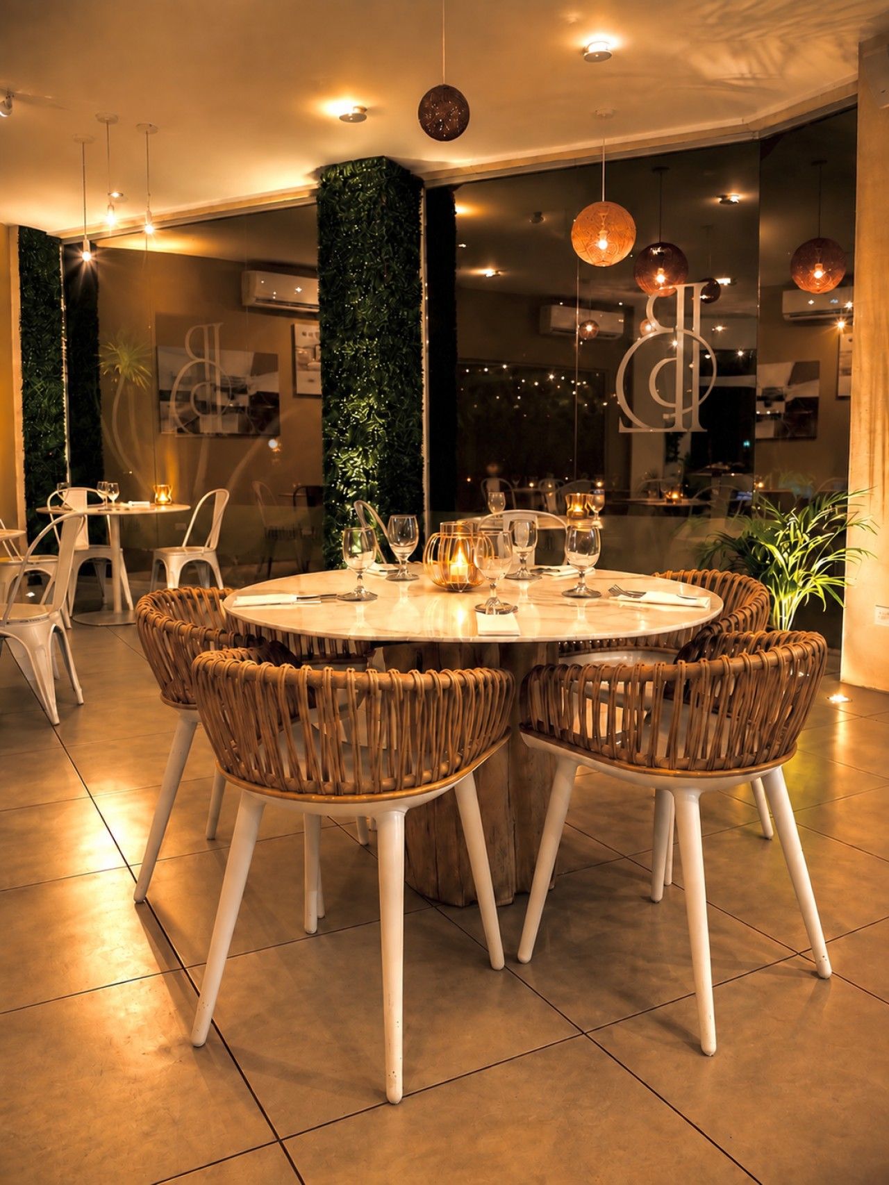 A dining area with a round table, wicker chairs, and a glass partition.