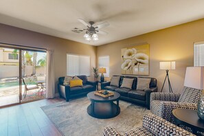 A living room with a ceiling fan, two sofas, a coffee table, and a large flower painting on the wall. - inviting home with private pool, patio, grill, washer/dryer, & central AC (Chandler)