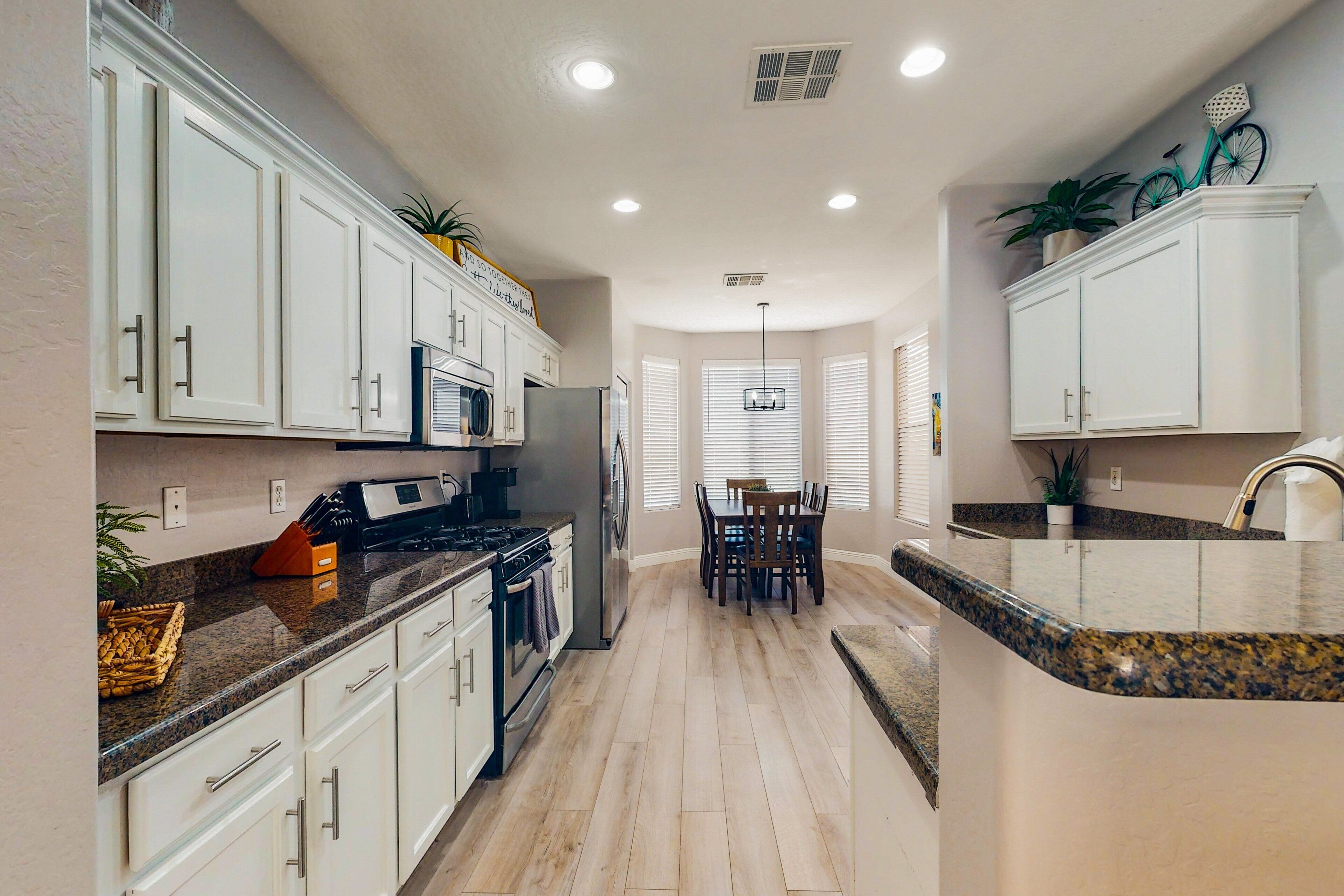 A modern kitchen with white cabinets, granite countertops, and a central island.