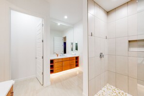 A modern bathroom with a large mirror, a vanity with a sink, and a shower area.