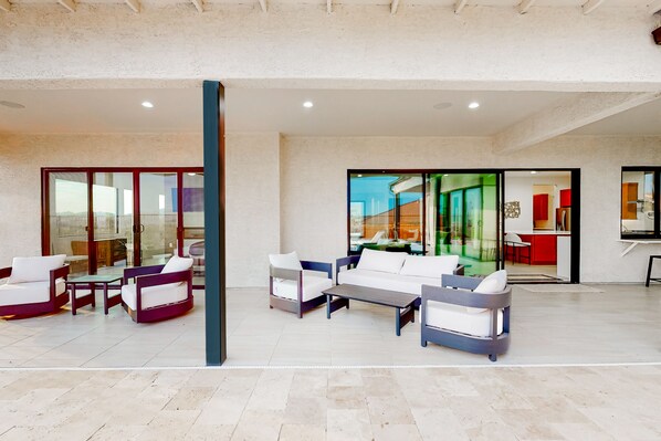 A spacious indoor area with modern furniture, including sofas and chairs, and large glass doors leading to an outdoor area.