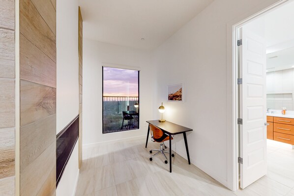A modern office space with a desk, chair, and large window.