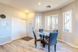 A dining area with a round table, blue chairs, and a clock on the wall. - Bright and spacious mountain-view home with pool/hot tub on-site, golfing nearby (Oro Valley)