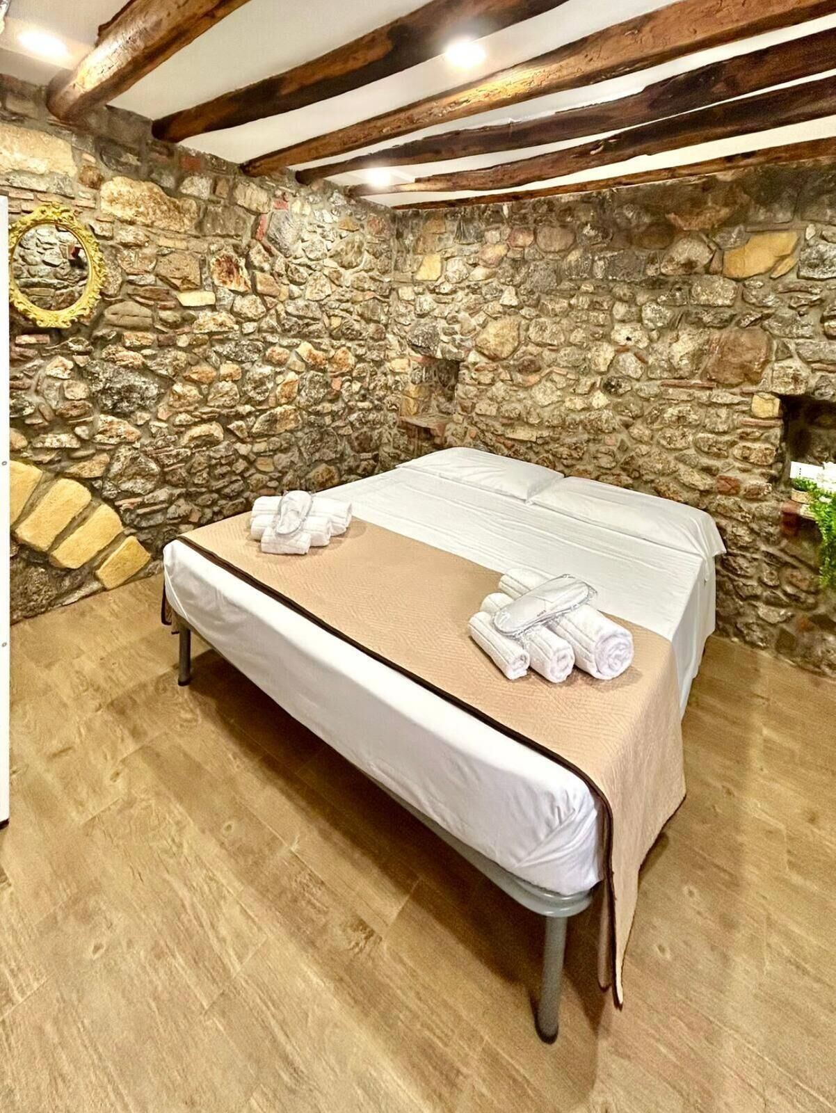 A massage table with towels, set against a stone wall and wooden beams.