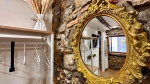 Un miroir doté d’un cadre doré orné, placé contre un mur de pierre.