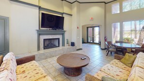 A spacious lobby with a fireplace, comfortable seating, a television, and large windows.