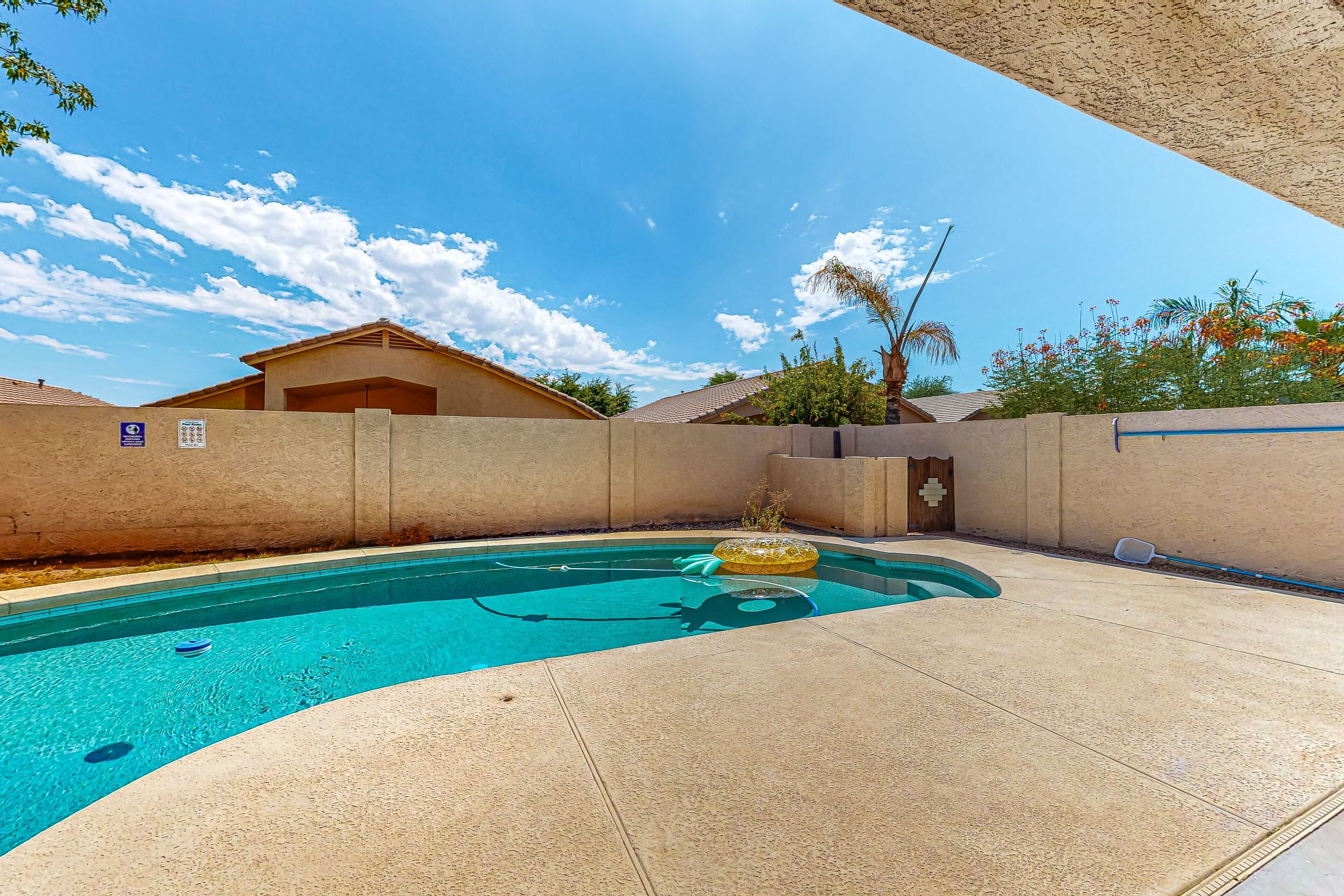 A swimming pool with a clear blue water, a yellow inflatable float, and a concrete deck.