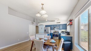 A modern kitchen with blue cabinets, a dining table with chairs, and a large window. - Updated home with private pool, enclosed yard, covered patio, grill, & W/D (Glendale)