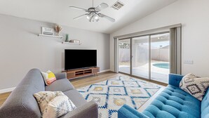 A modern living room with a flat-screen TV, two sofas, a patterned rug, and a ceiling fan. - Updated home with private pool, enclosed yard, covered patio, grill, & W/D (Glendale)