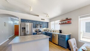 A modern kitchen with blue cabinets, stainless steel appliances, and a marble countertop island. - Updated home with private pool, enclosed yard, covered patio, grill, & W/D (Glendale)