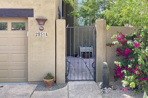 A beige house with a garage door, a gate, and a potted plant. - Luxe home near outdoor adventure with pool & furnished patio - dog-friendly (Scottsdale)