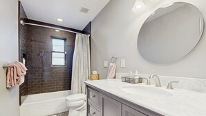A bathroom with a bathtub, toilet, vanity with a mirror, and a patterned rug. - Sun-soaked & charming dog-friendly retreat with private pool, large patio, & W/D (Tucson)