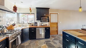A modern kitchen with a central island, built-in appliances, and a stone backsplash. - Sun-soaked & charming dog-friendly retreat with private pool, large patio, & W/D (Tucson)