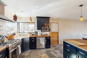 A modern kitchen with a central island, built-in appliances, and a stone backsplash.
