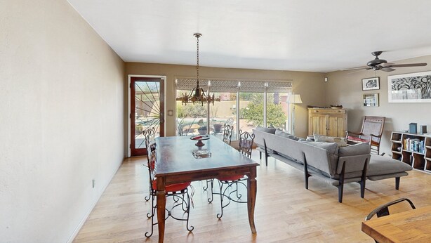 A spacious dining area with a wooden table and chairs, a chandelier, and a view of the outdoors through large windows. - Sun-soaked & charming dog-friendly retreat with private pool, large patio, & W/D (Tucson)