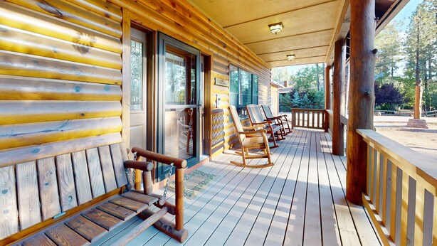 Eine Holzhütte mit Veranda, Schaukelstühlen und einer Bank.