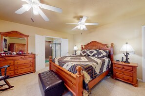 Ein Schlafzimmer mit einem hölzernen Bett, einem Nachttisch, einer Kommode, einem Schaukelstuhl und einem Deckenventilator.