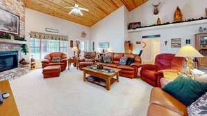 Ein geräumiges Wohnzimmer mit Ledersofas, einem Kamin, Holzboden und einem aufgehängten Hirschkopf.
