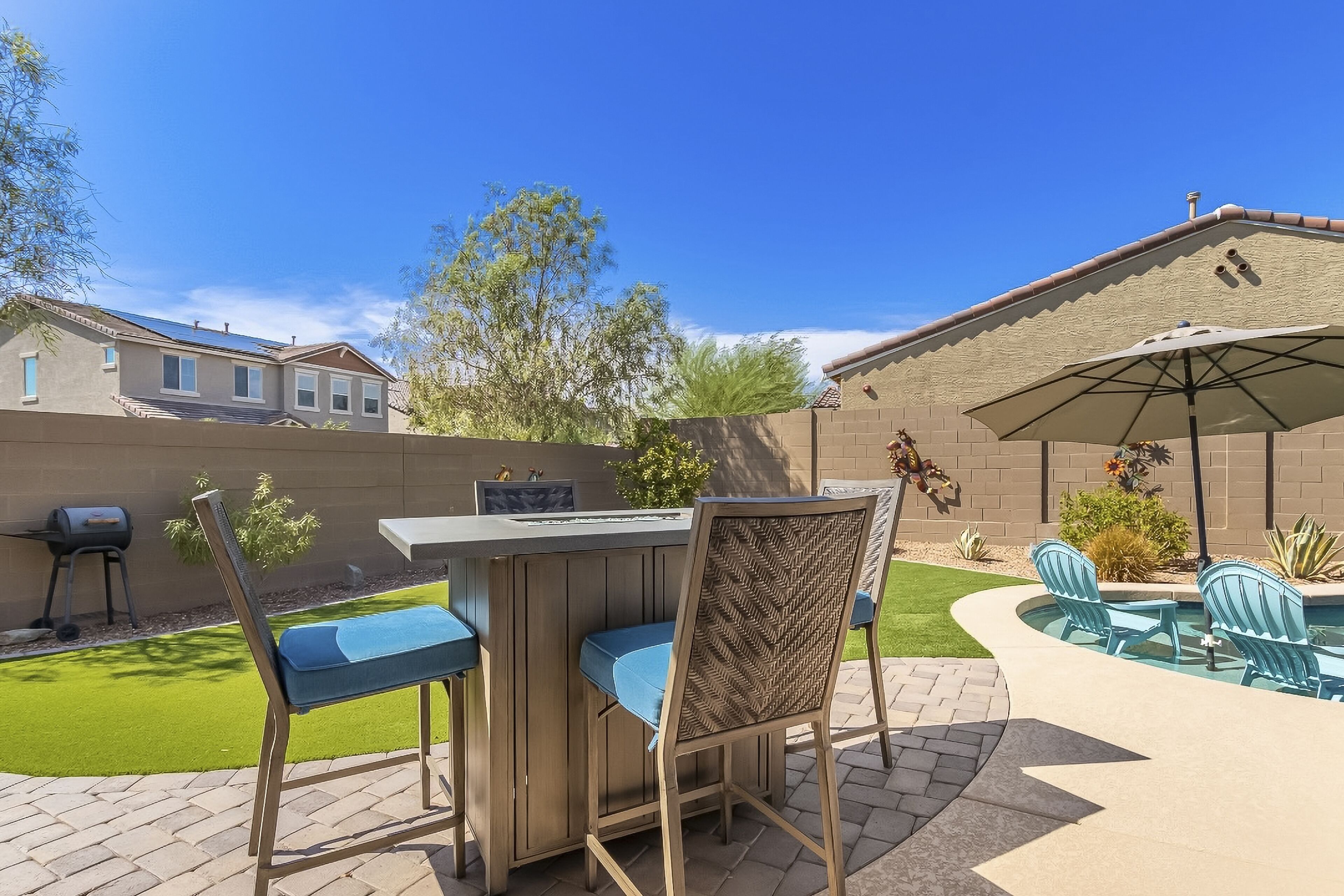 An outdoor patio with a bar, chairs, and a pool area.