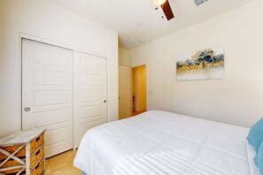 Un dormitori amb un llit gran, parets blanques i una porta que dona a una altra habitació.