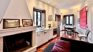 Cozinha moderna com lareira, sala de jantar e sala de estar com sofá.