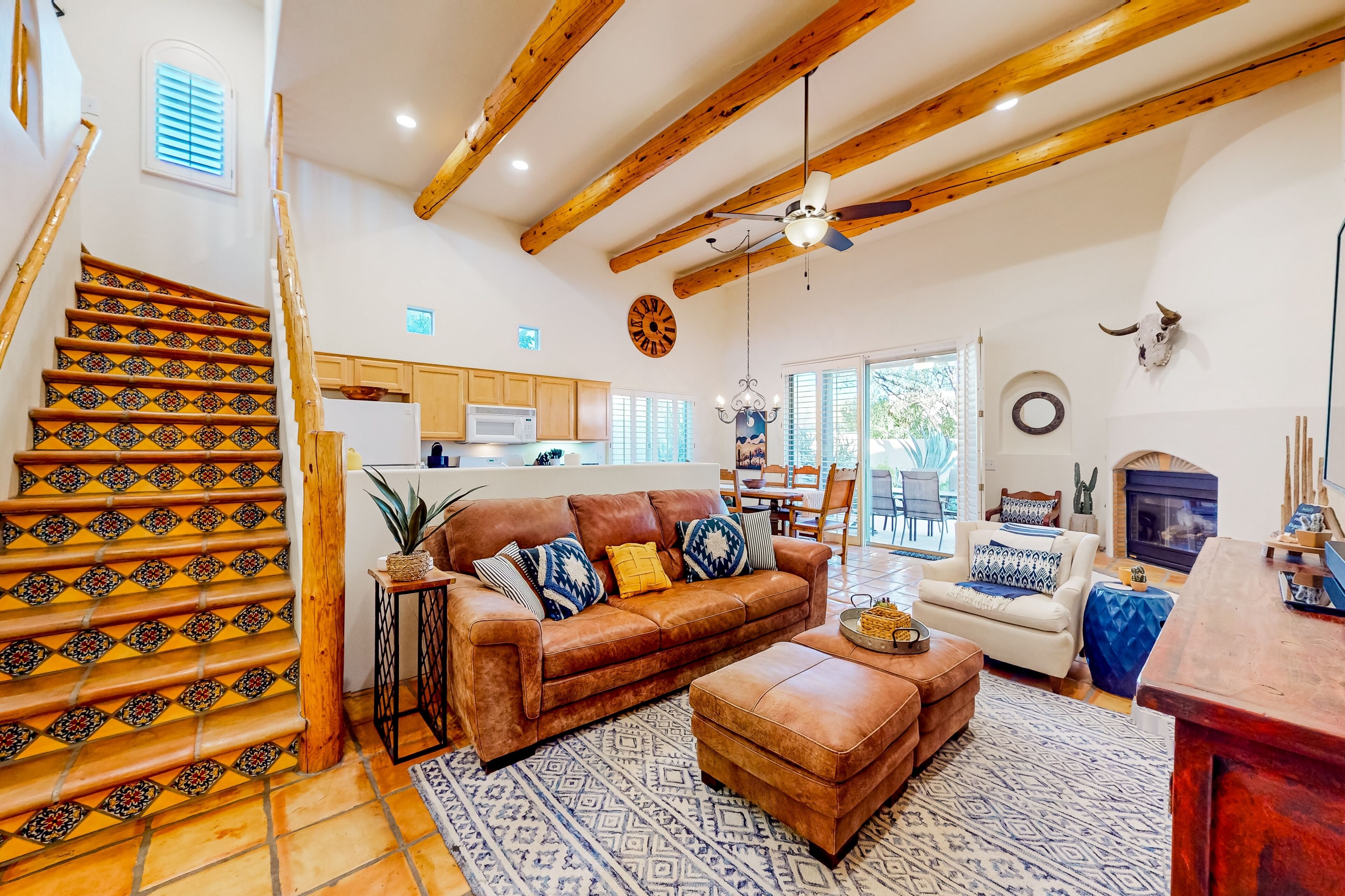 A spacious living area with a staircase, a sofa set, a dining table, and a fireplace.
