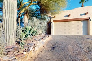 A desert landscape with a cactus, a stone wall, and a garage door.