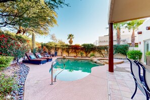 Zona de piscina amb gandules, una piscina i vegetació circumdant.