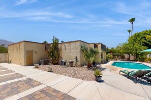 A residential property with a swimming pool, outdoor seating, and a small building with a door and windows. - Recently Remodeled Home | Fenced Backyard, Heated Pool, Grill & Fire Pit (Palm Springs)