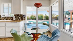 A modern kitchen with white cabinets, a glass dining table, and a view of a swimming pool. - Updated mid-century gem with private pool, spa, gas grill, and free WiFi (Palm Springs)