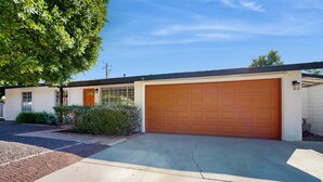 A single-story house with a garage, a front door, and a large tree to the left. - Updated mid-century gem with private pool, spa, gas grill, and free WiFi (Palm Springs)
