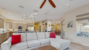 Ein modernes Wohnzimmer mit einer Eckcouch, einem Holztisch und einem Deckenventilator.
