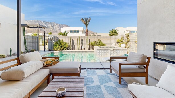 A modern outdoor lounge area with a pool, seating, and a view of mountains. - Desert days, cozy nights, and poolside delights await at this stylish home. (Palm Springs)