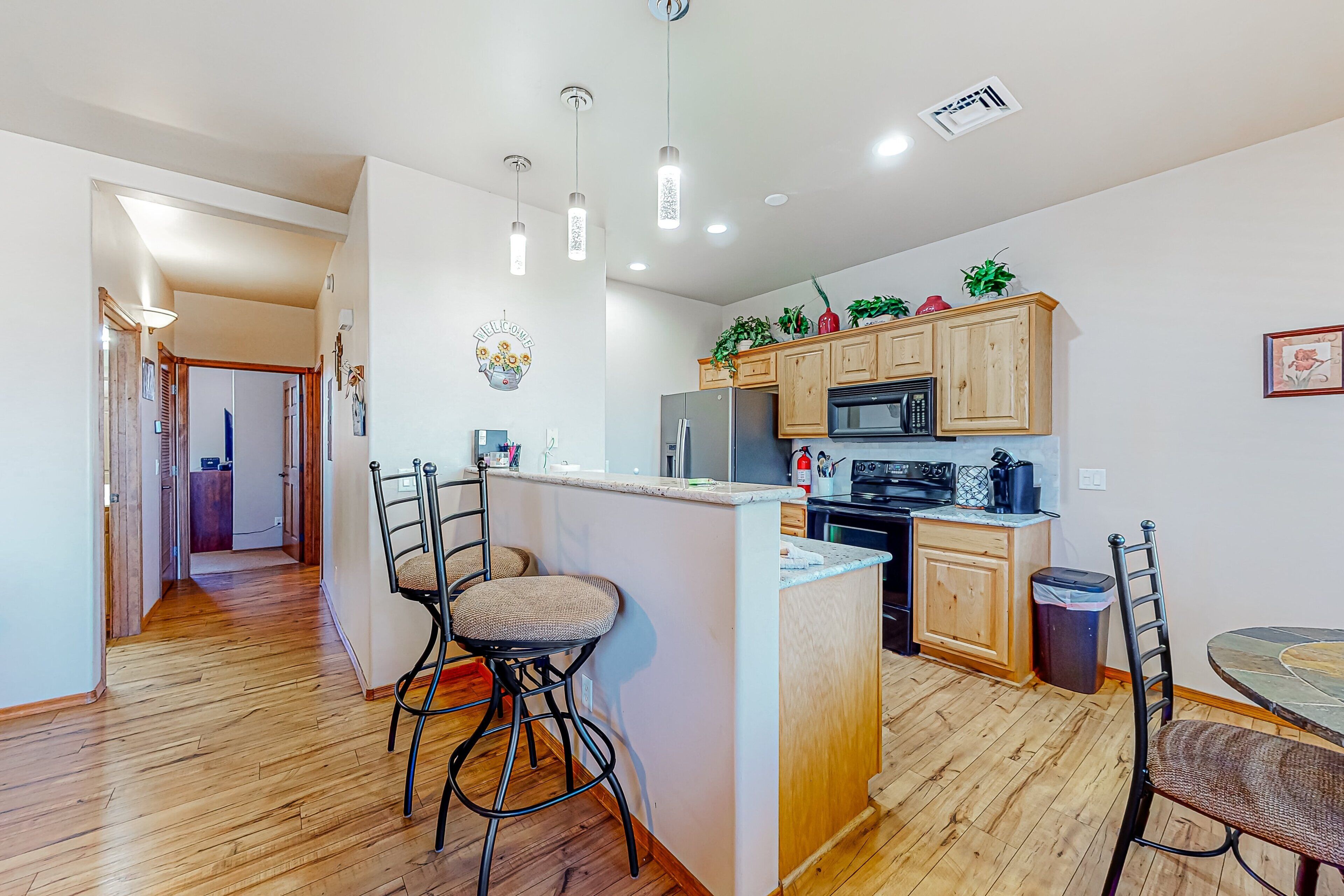 A modern kitchen with wooden cabinets, a central island, and bar stools.
