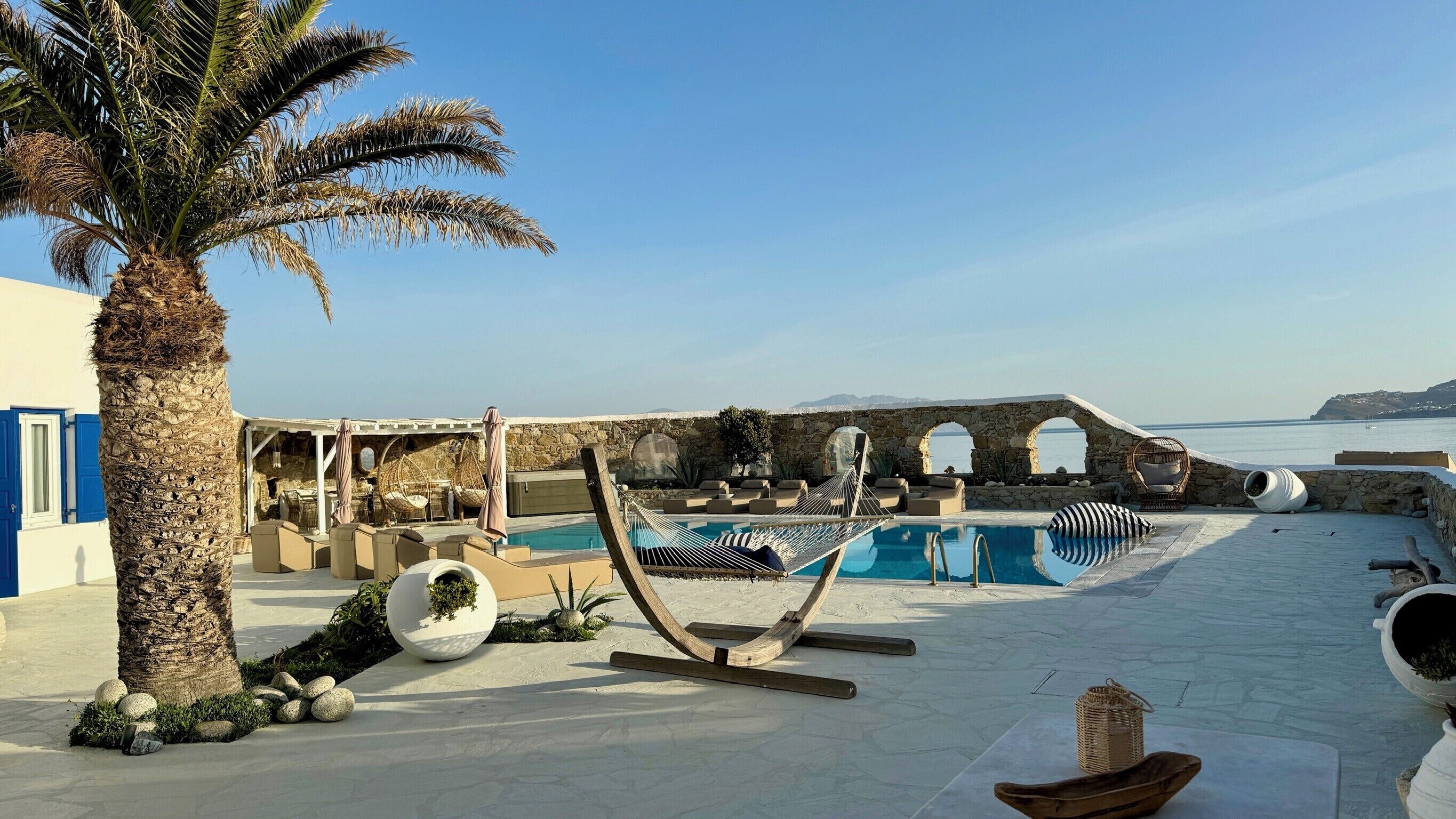 A poolside area with a hammock, lounge chairs, and a view of the sea.