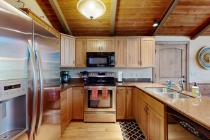 Een keuken met houten kastjes, roestvrijstalen apparatuur, een magnetron, oven en vaatwasser.