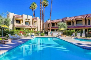 Une piscine avec des chaises longues et des palmiers.