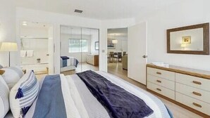 Een moderne slaapkamer met een bed, nachtkastjes, een kledingkast en een spiegel.