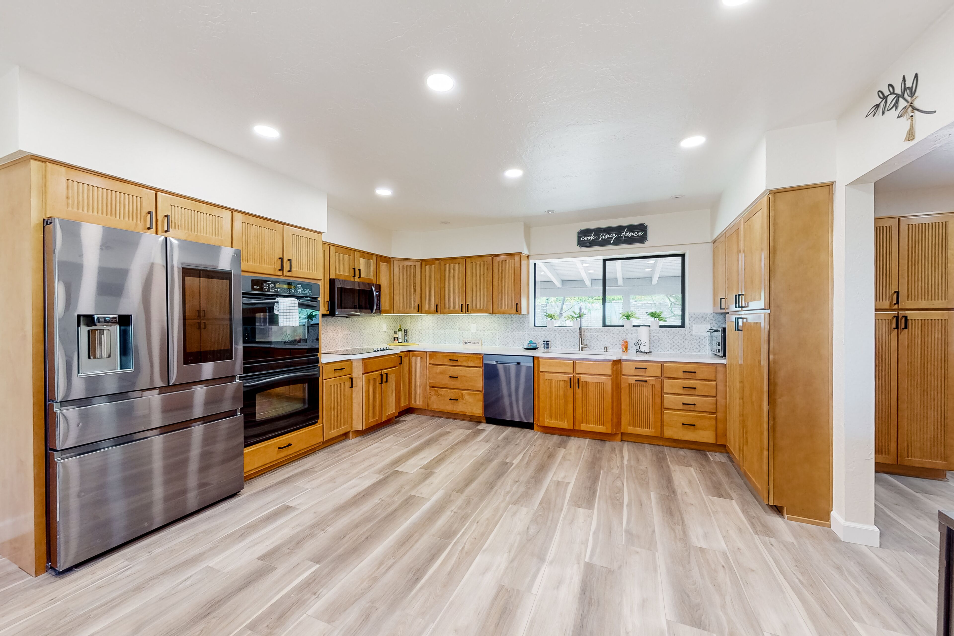 Una cocina moderna con gabinetes de madera, electrodomésticos de acero inoxidable y un ventanal grande.