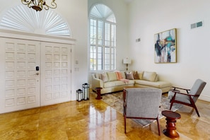 A spacious living room with a large arched window, a beige sofa, two armchairs, a coffee table, and a painting on the wall. - Family-friendly luxury home in Estate Groves with private pool & cabana + WiFi (Mesa)