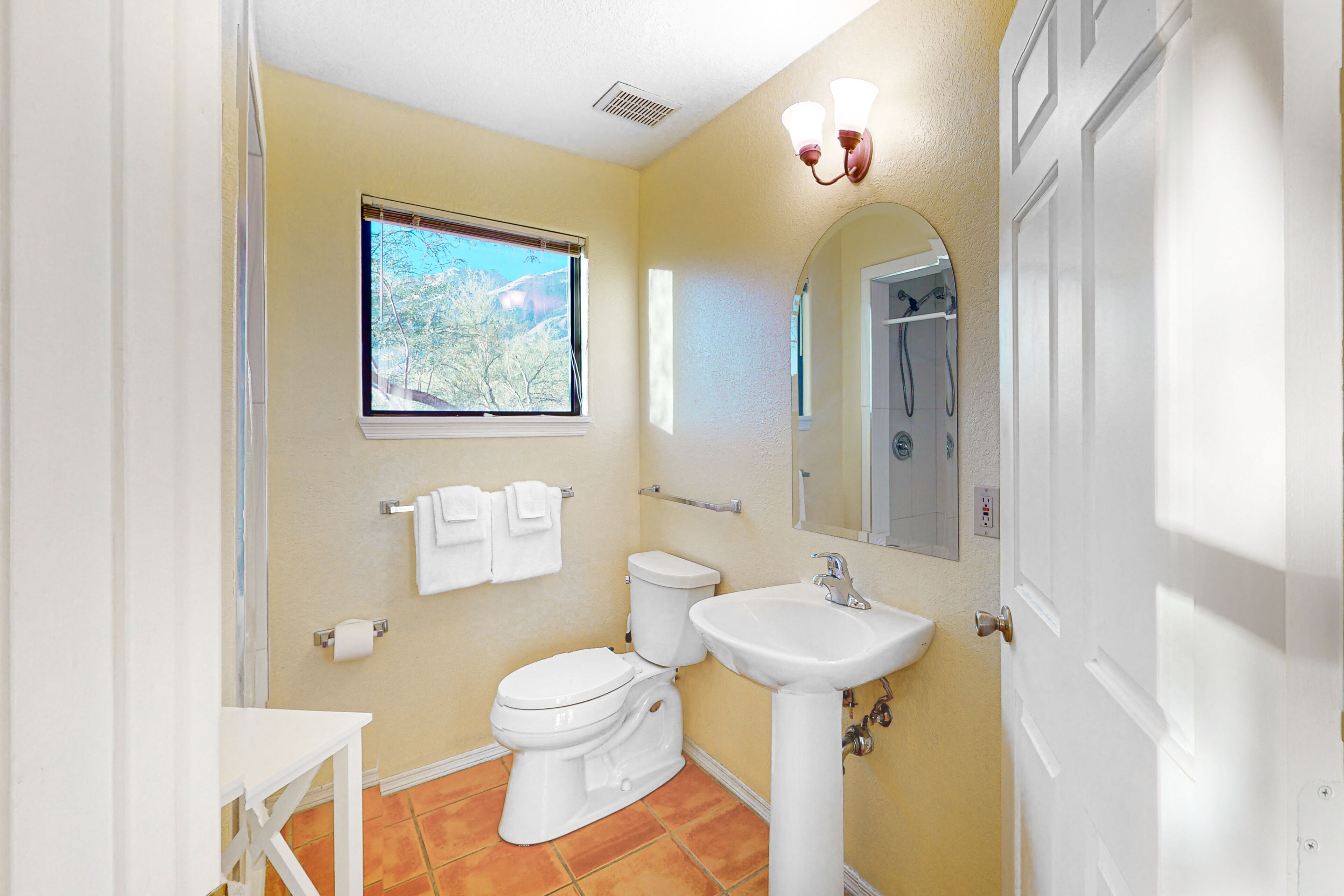A bathroom with a toilet, sink, and window.