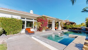 Ein modernes Haus mit Swimmingpool, Sitzgelegenheiten im Freien und üppiger Bepflanzung.
